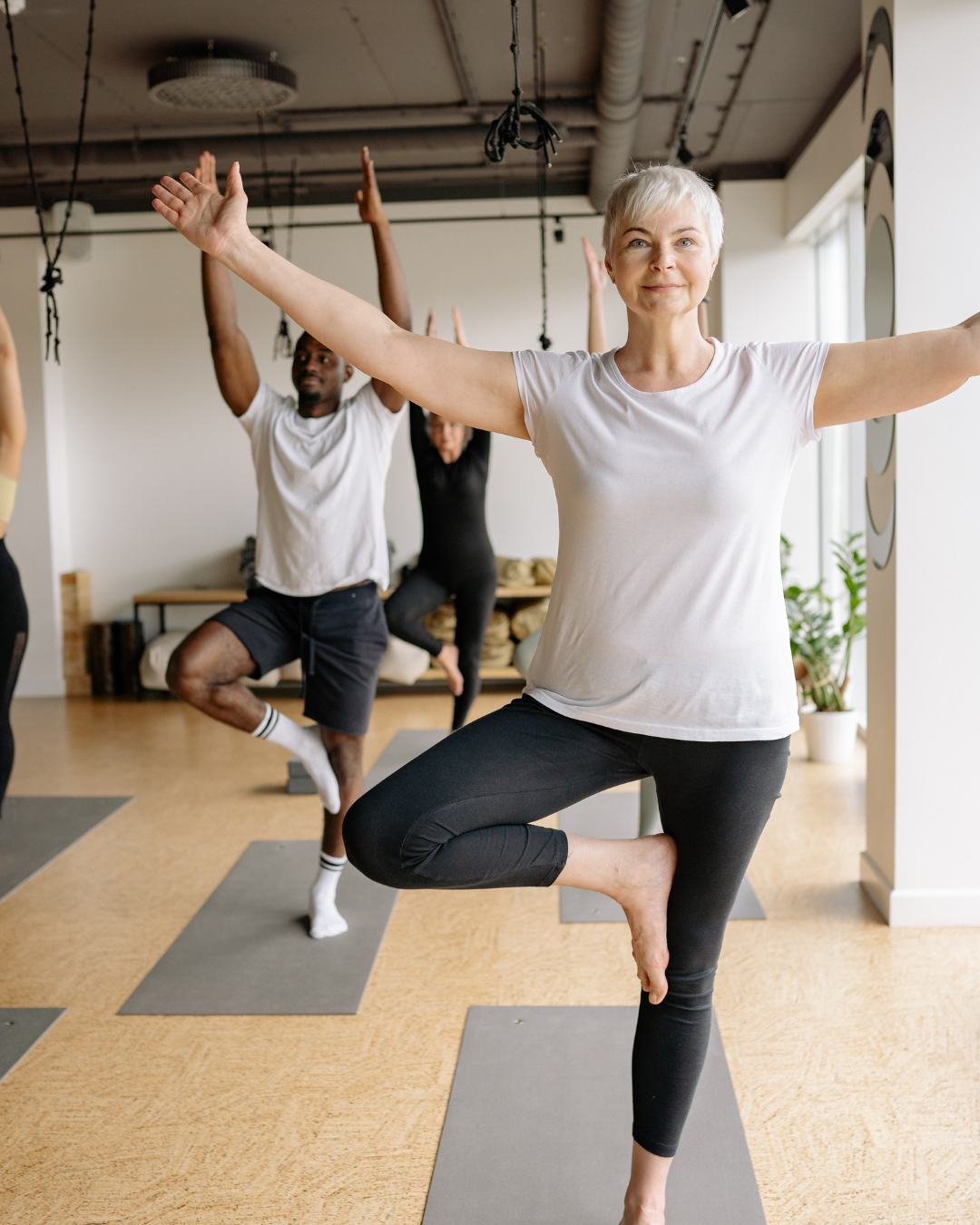 Active older woman in t-shirt and leggings holds a yoga pose.