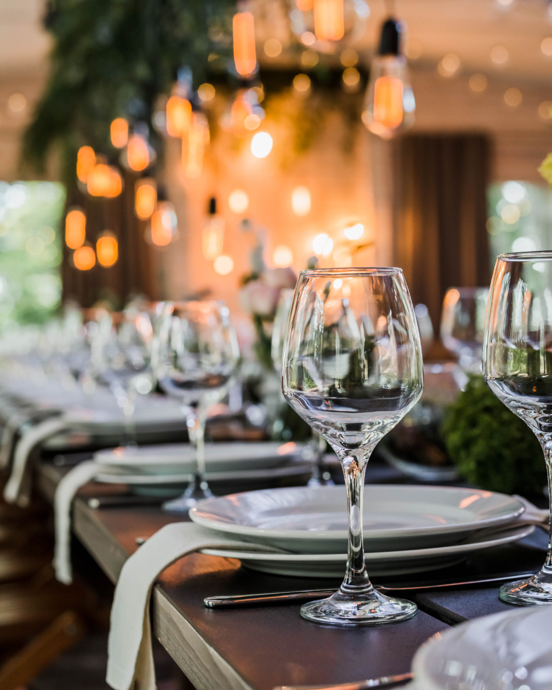A table is set with plates, napkins, and glass stemware for an event.