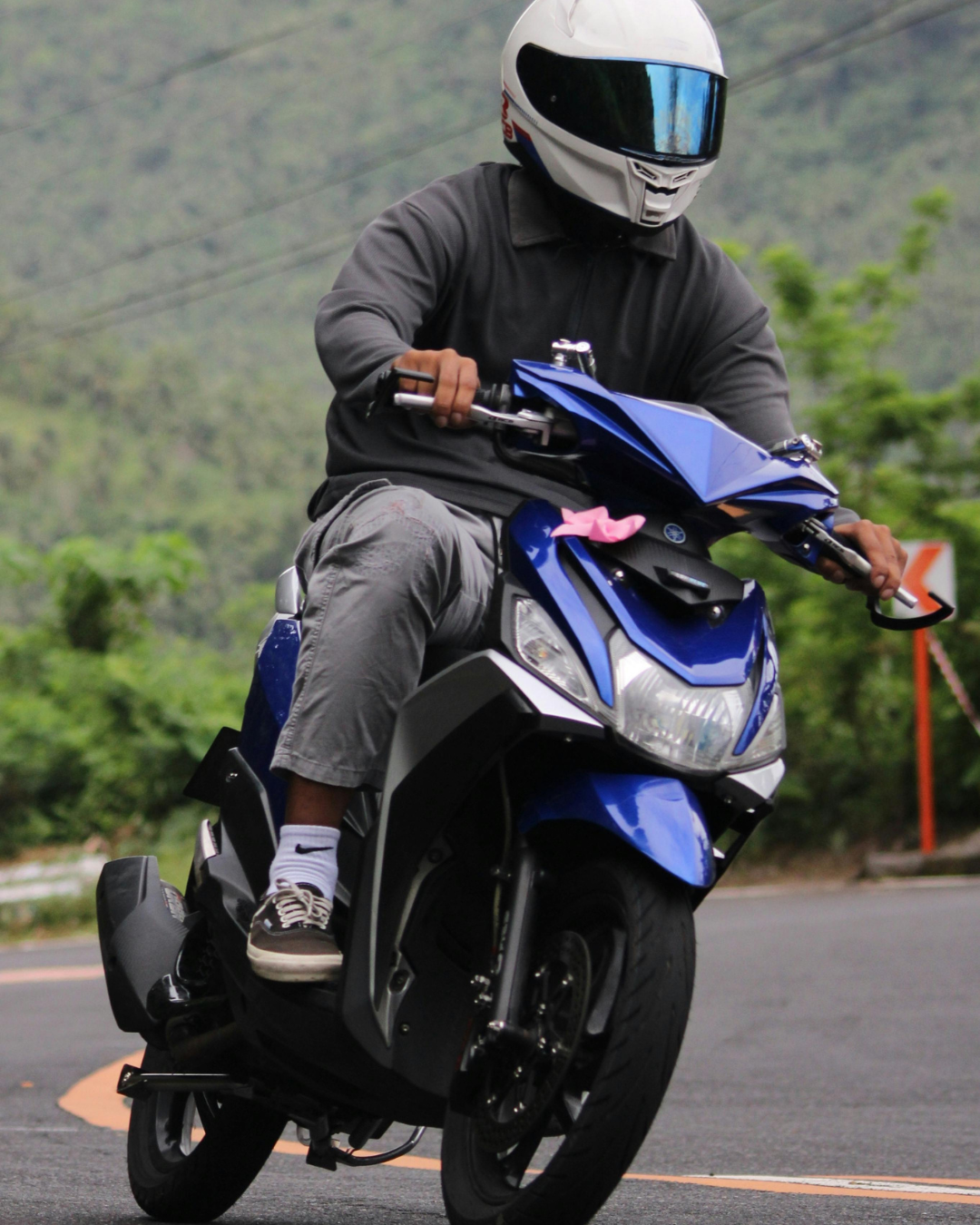 A man driving a blue motorcycle through the mountains.