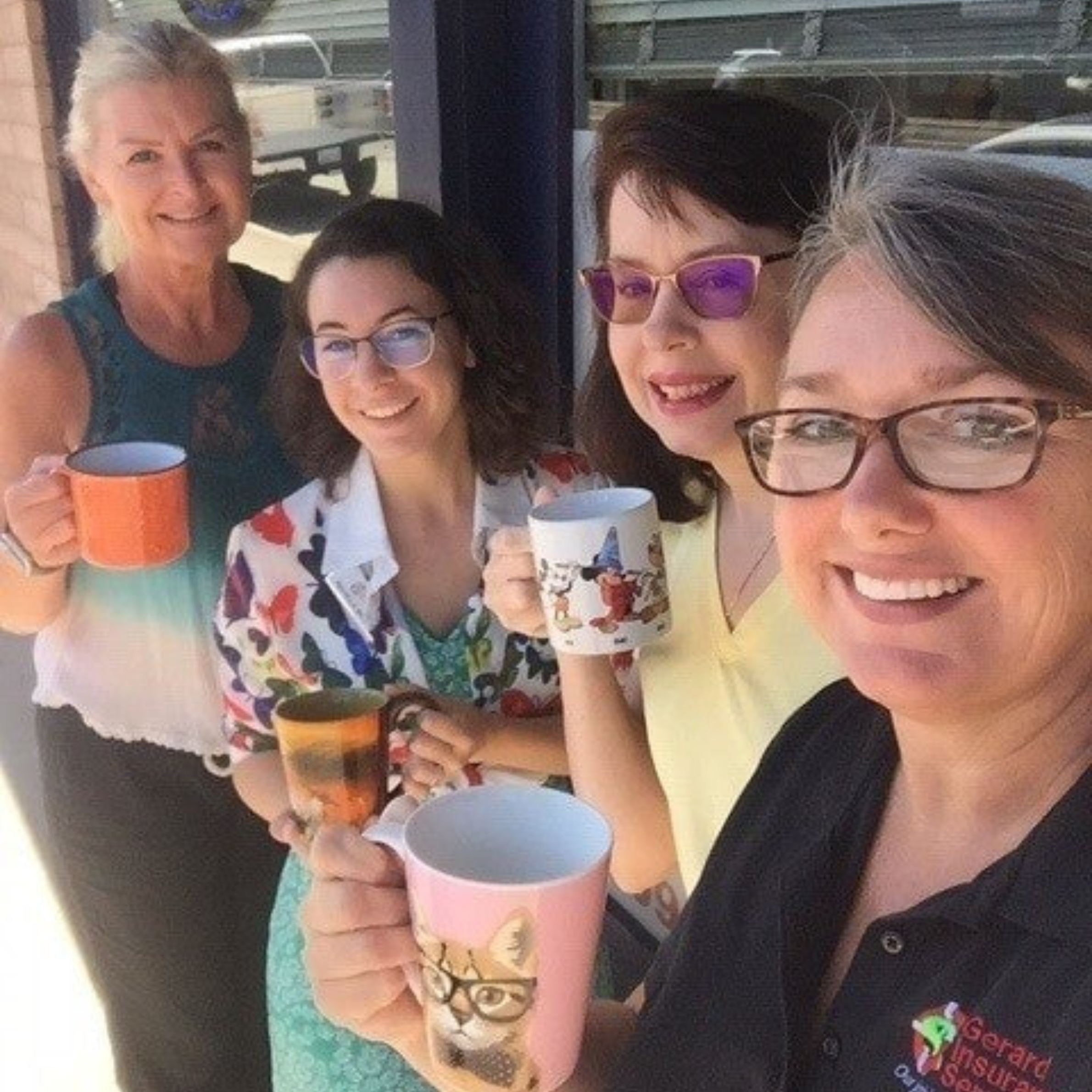 Four team members from Gerard Insurance Services holding coffee mugs outside of the San Andreas office.
