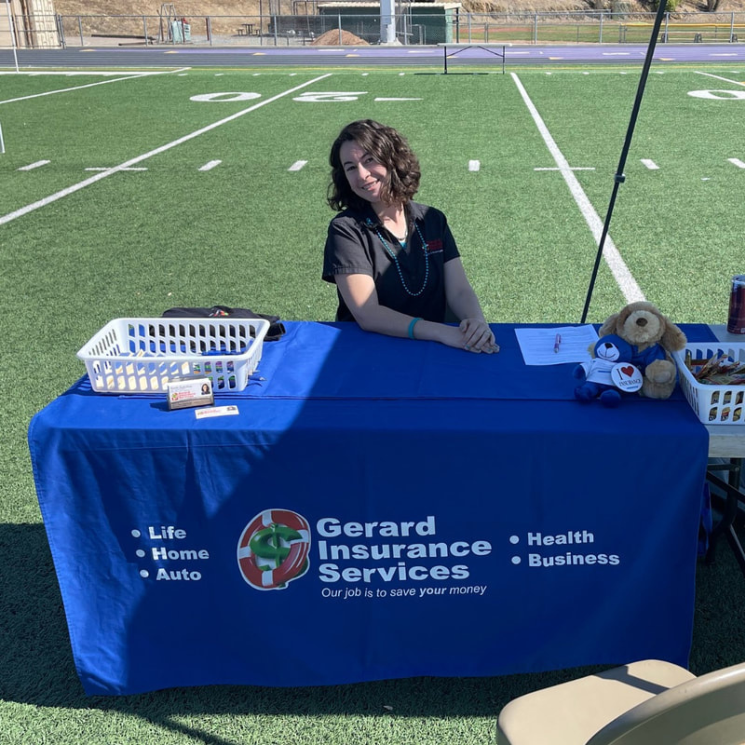 On the Right Track Gerard Insurance Services staff member sitting at the booth on the football field during On the Right Track.